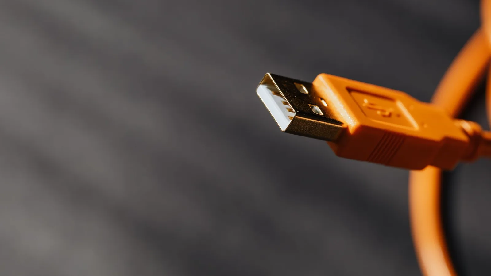 Mão conectando um adaptador USB em uma porta de computador moderno para encaixar um scanner antigo, mostrando os diferentes tipos de conector USB.